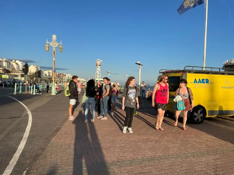 A group of young people on Brighton seafront on a summer evening