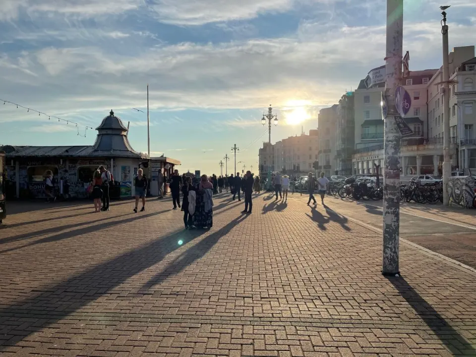Набережная на побережье Англии вечером, люди идут вдоль воды