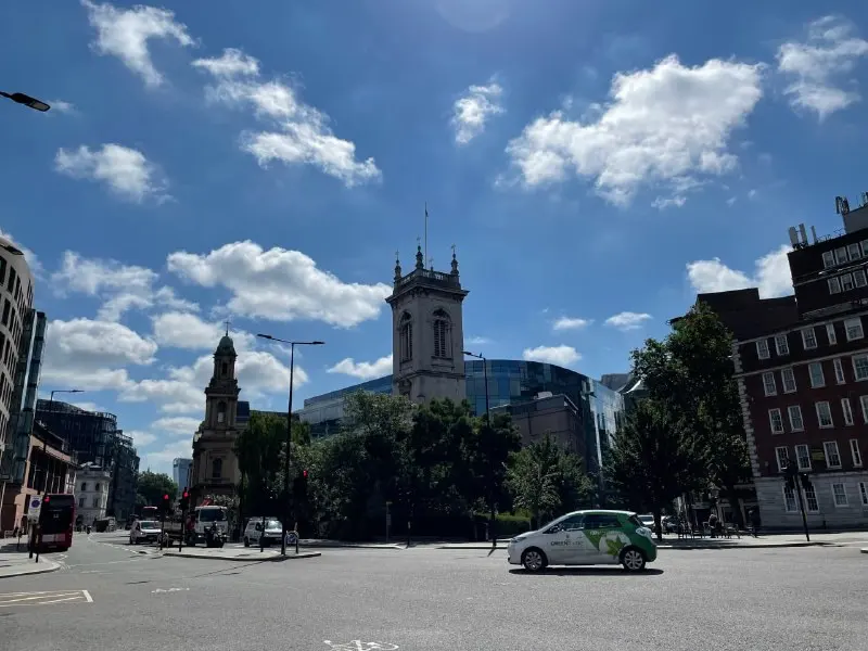 A junction in the City of London: road, cars and an old church among office buildings