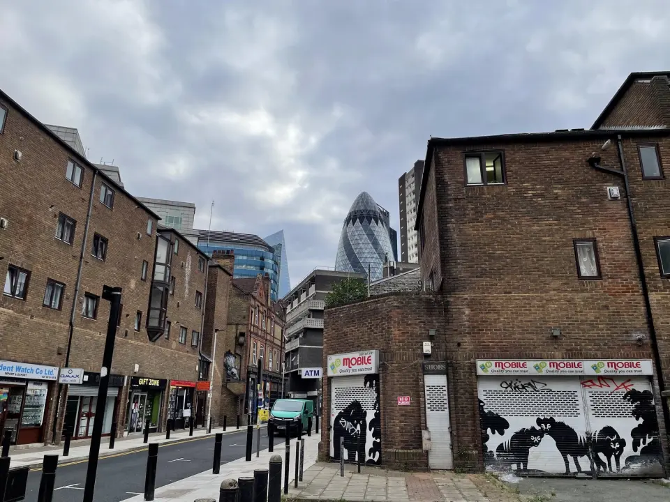 A London street of brick buildings with the Gherkin tower in the distance