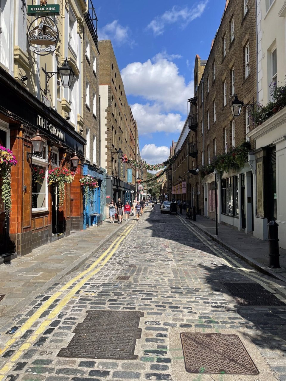 A cobbled street in Covent Garden with a pub and passers-by