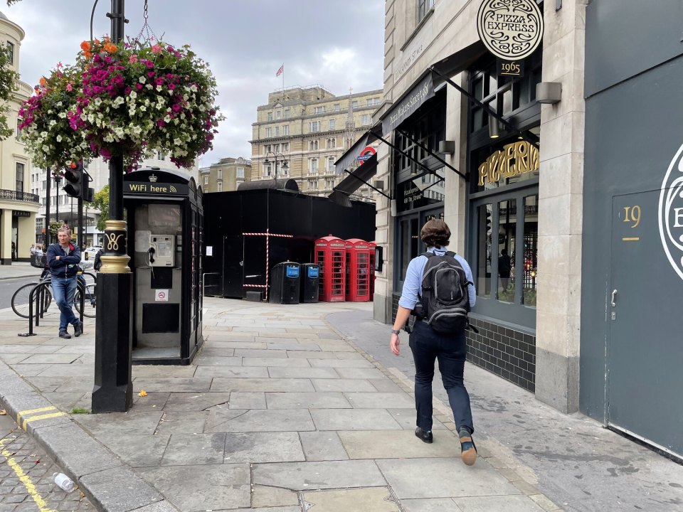 A central London street with shops, pedestrians and telephone boxes