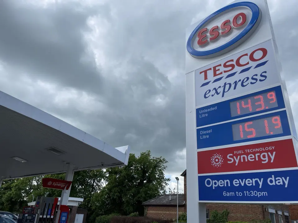 Price board at a UK petrol station next to a Tesco Express