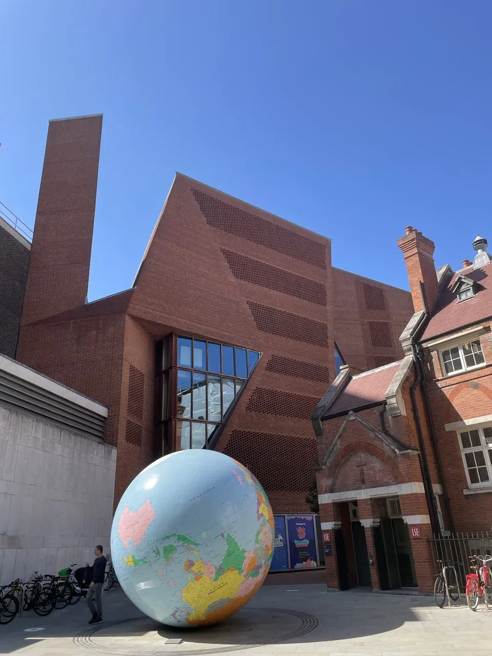 A large globe in the courtyard of the London School of Economics beside a modern brick building