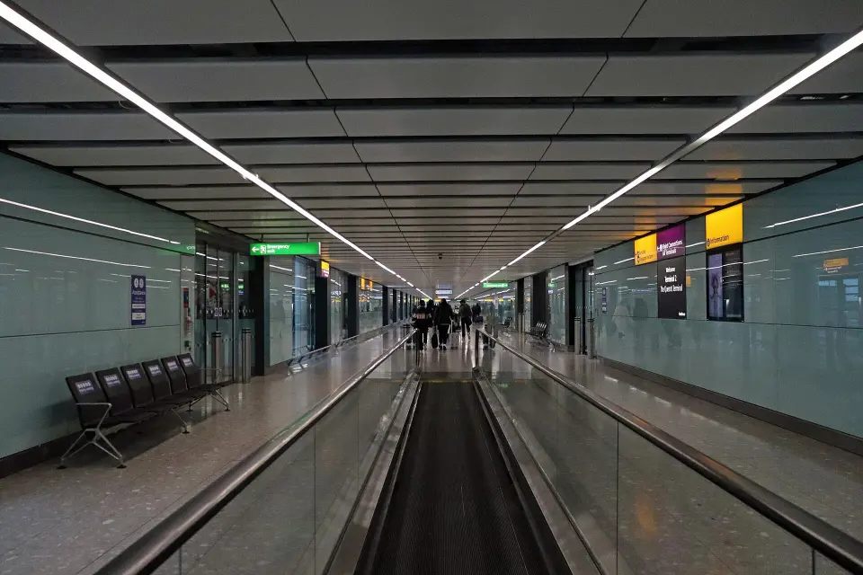 A long arrivals corridor at Heathrow Terminal 2 with a travelator and signage