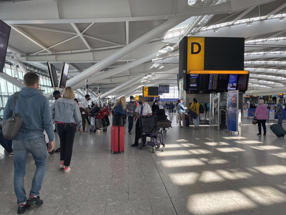 Heathrow terminal concourse, passengers with suitcases by the check-in desks and departure boards