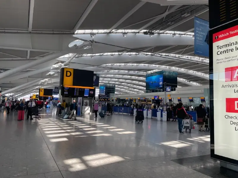 Passengers with bags walking along an airport corridor towards baggage claim