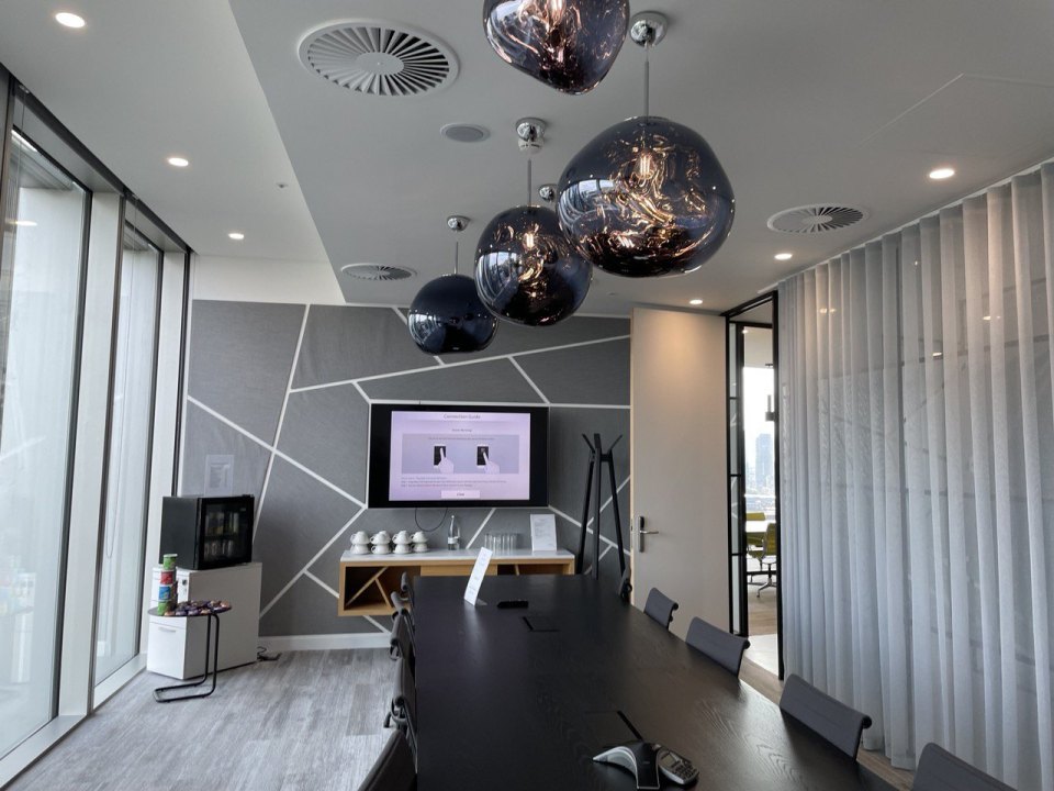 An empty boardroom in a City of London office tower, with a long table and a wall screen