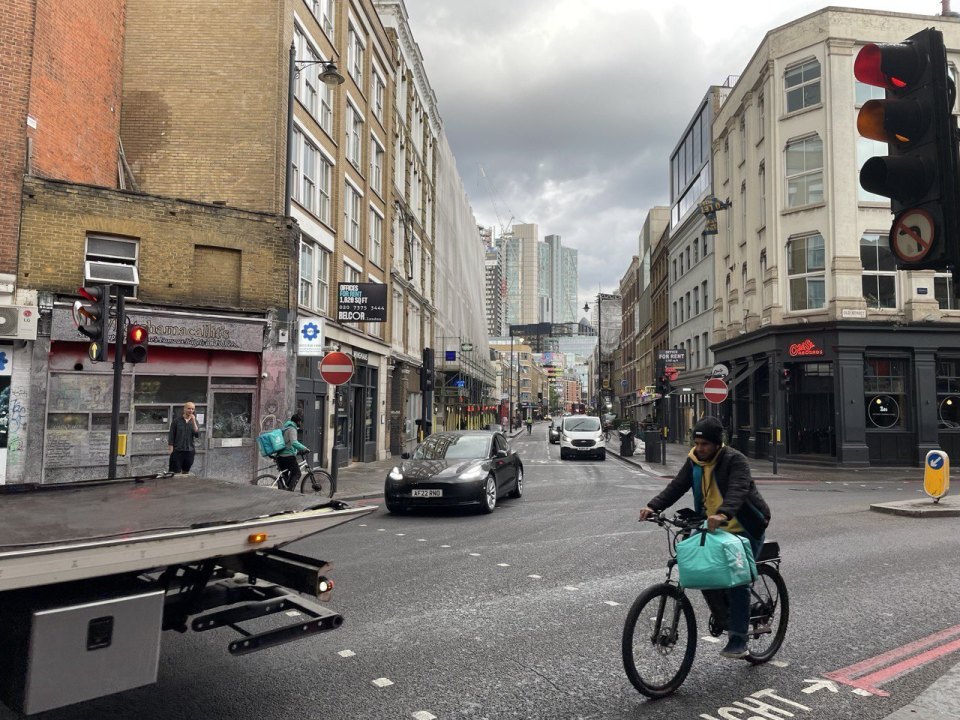 Two cycle couriers carrying delivery bags on a London street