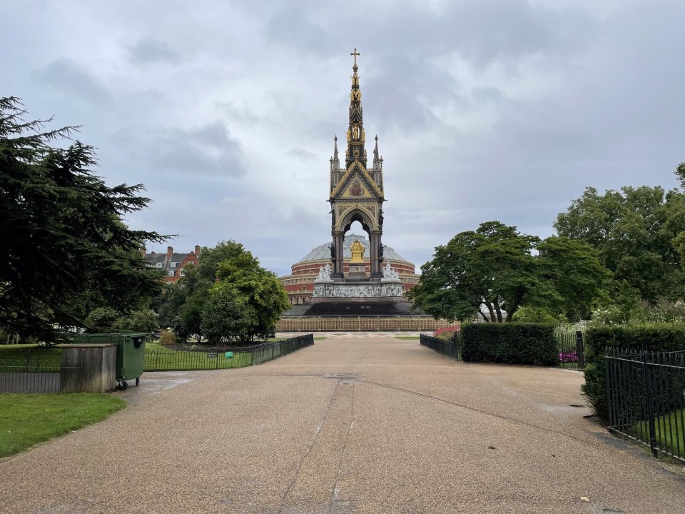 A tree-lined path in a London park with the Albert Memorial in the distance