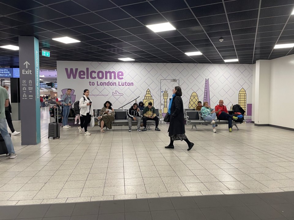 Зал прилёта аэропорта Лондон-Лутон с надписью Welcome to London Luton и пассажирами с чемоданами