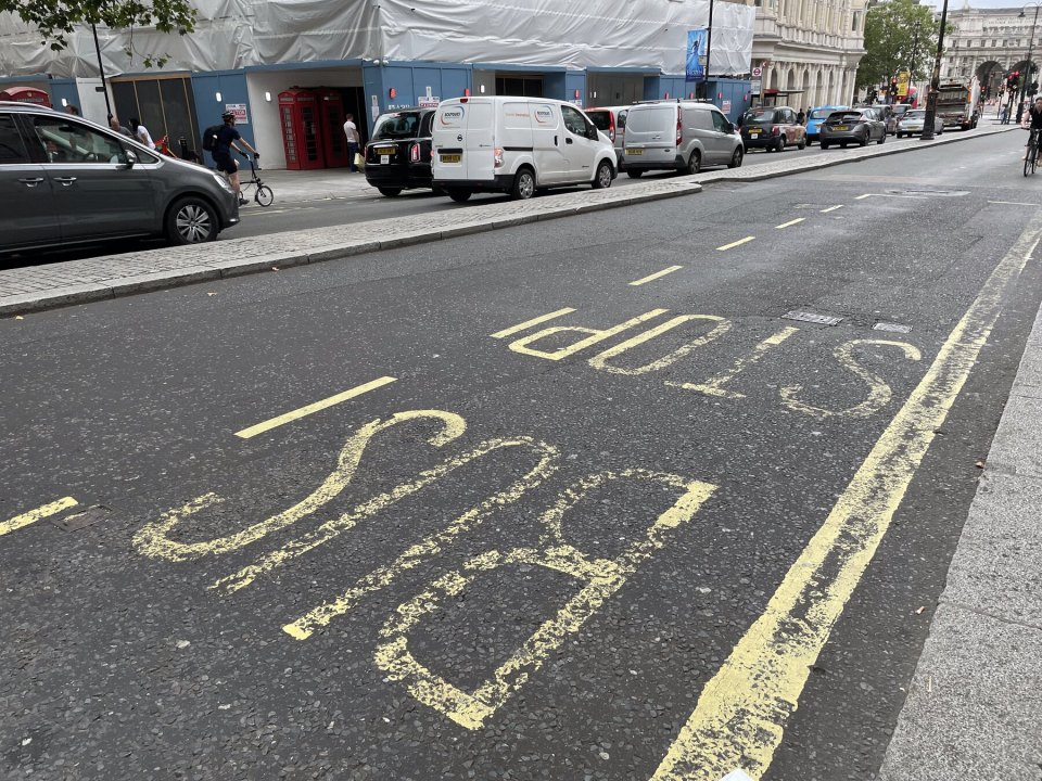 Worn asphalt road surface on a London street with faded BUS STOP markings