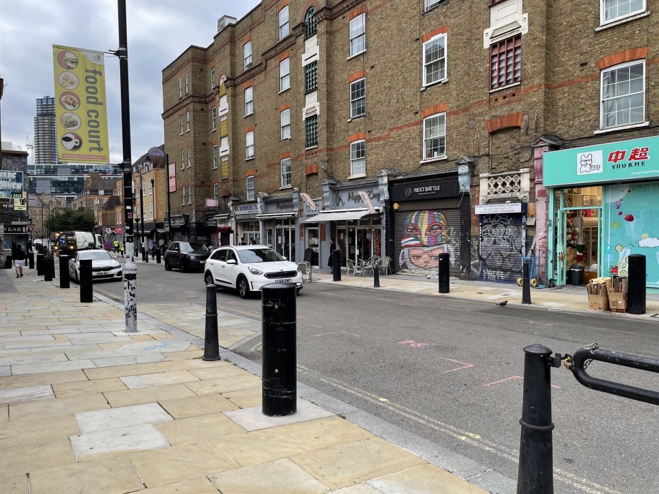 London street with parked cars and a row of brick buildings