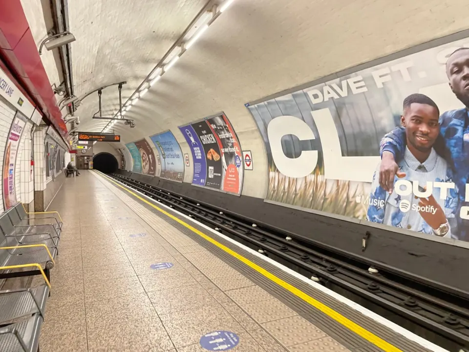 A London Underground platform lined with advertising posters