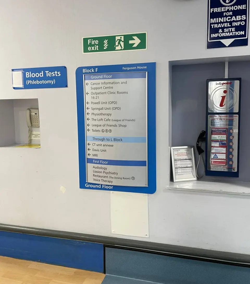 A Blood Tests sign and floor directory in the corridor of a British hospital