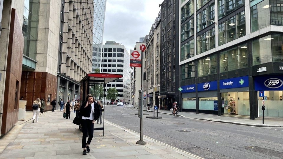 A woman walking through London's business district beside office buildings