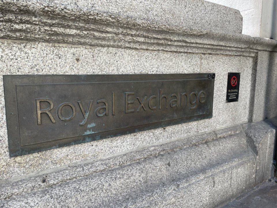 The bronze Royal Exchange plaque on the stone wall of the building in the City of London