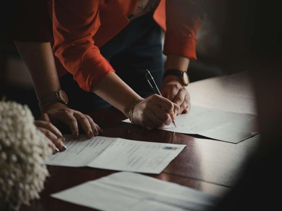A person signing a document with a pen