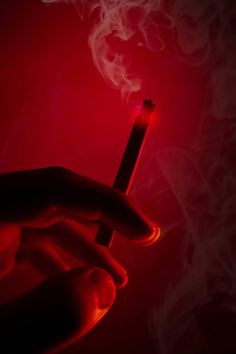 A lit cigarette held in a hand