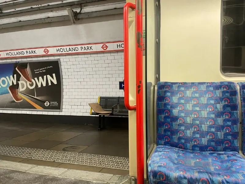 An empty London Underground carriage with blue seats and grab rails