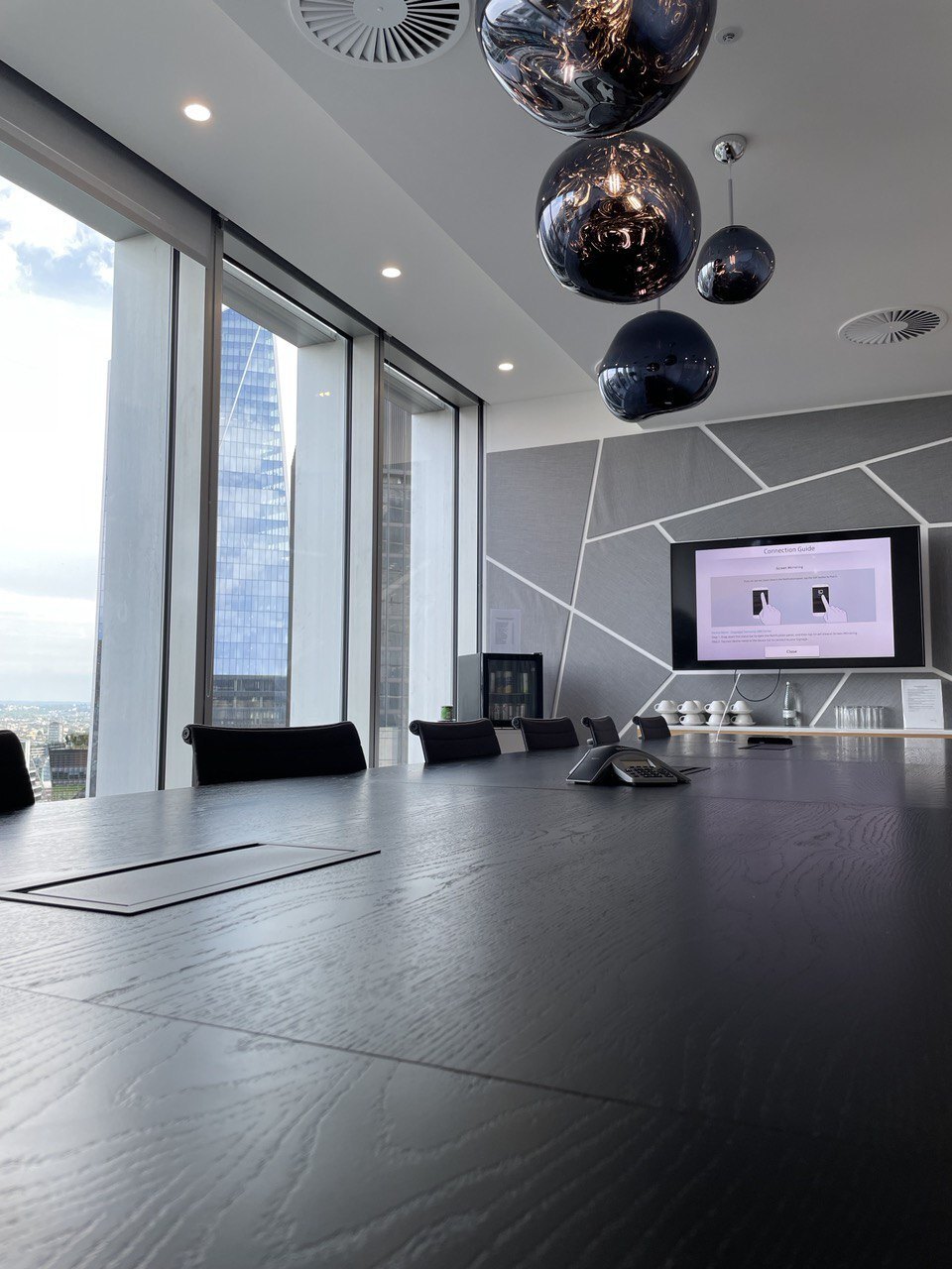 Meeting room with a screen and a view of London's business district