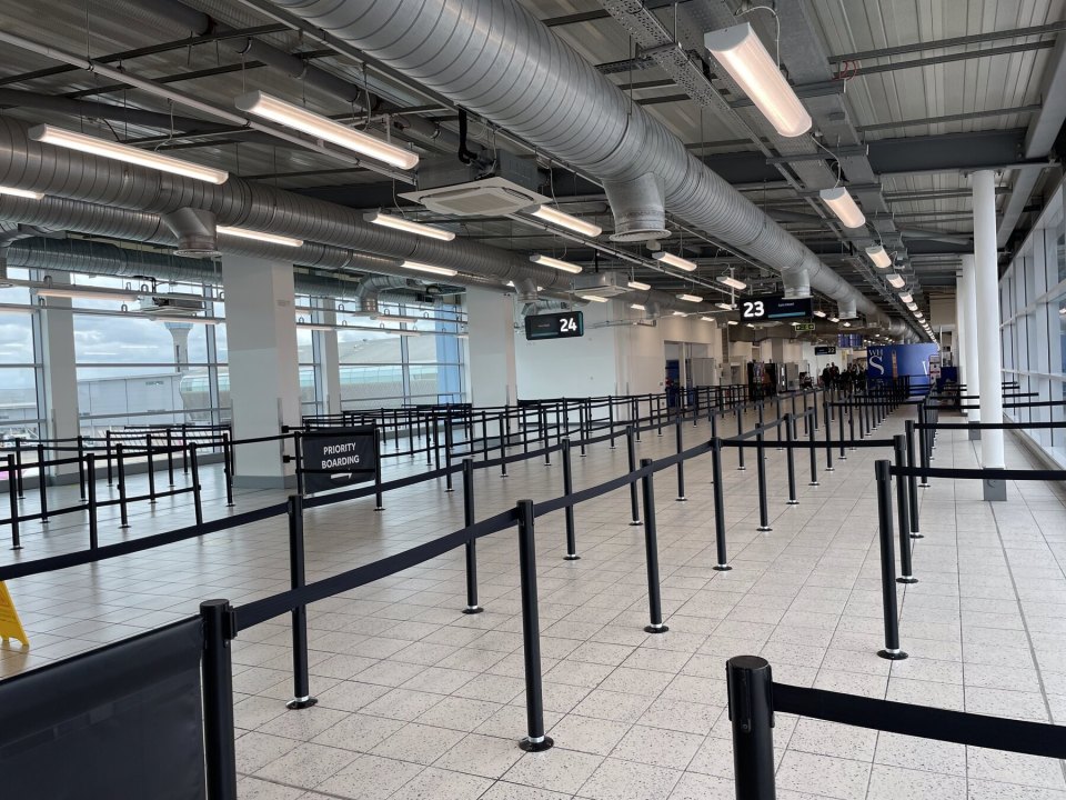 An empty British airport arrivals hall with queue barriers