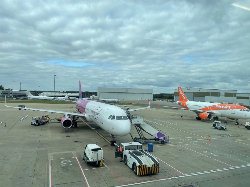 Departure lounge of a British airport with passengers and a flight board