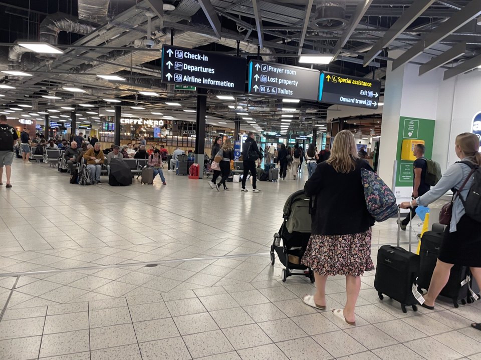 Указатели Check-in и Departures в зале британского аэропорта, пассажиры с чемоданами