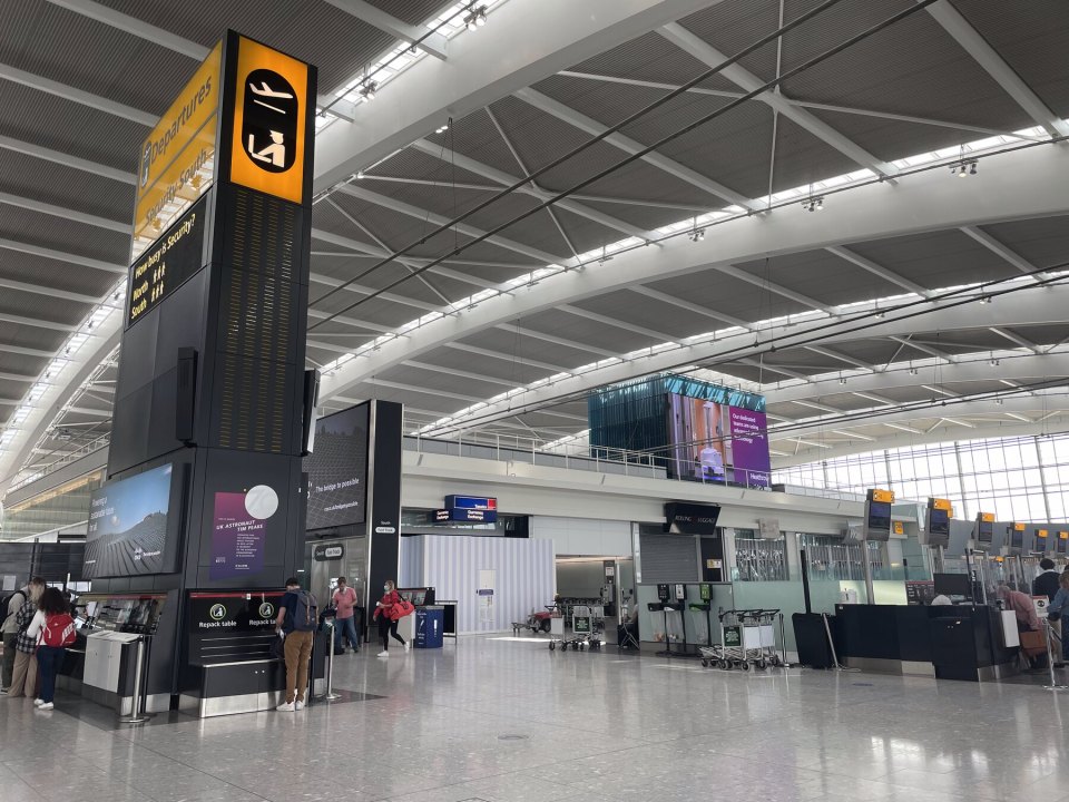 Check-in hall of a UK airport terminal with desks and signage