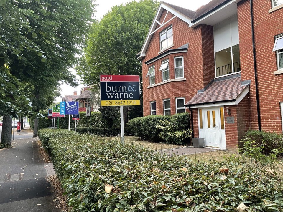 A suburban London block of flats with estate agent Sold and Let By boards by the hedge