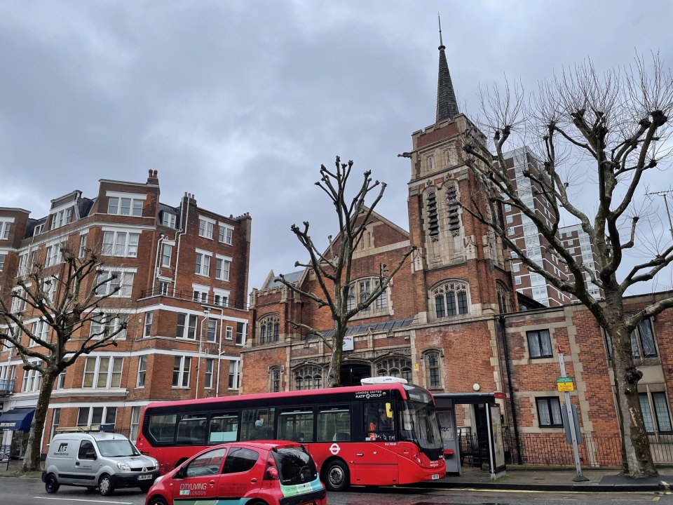Red-brick mansion flats on a London street with a bus at the stop