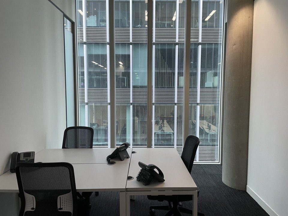 Empty desks, chairs and phones by a floor-to-ceiling office window
