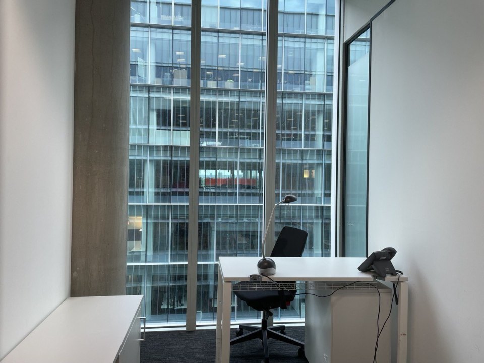 A desk and chair by a floor-to-ceiling office window
