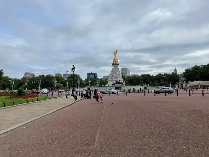 Pedestrians walking along the Mall towards the Victoria Memorial under an overcast sky