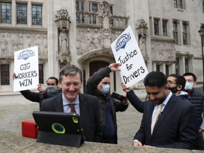 Водители Uber празднуют, слушая решение суда на планшете у здания Верховного суда в Лондоне